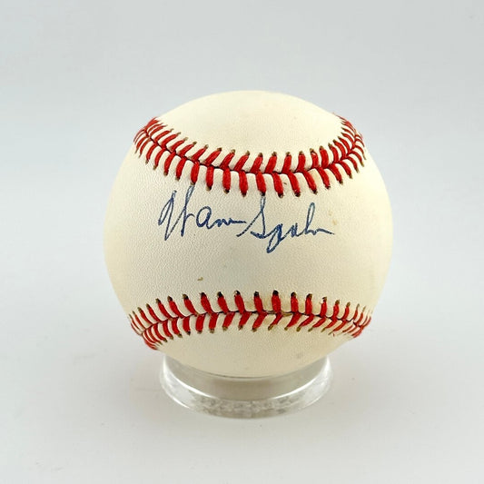 Baseball with red stitching on a clear stand against a white background