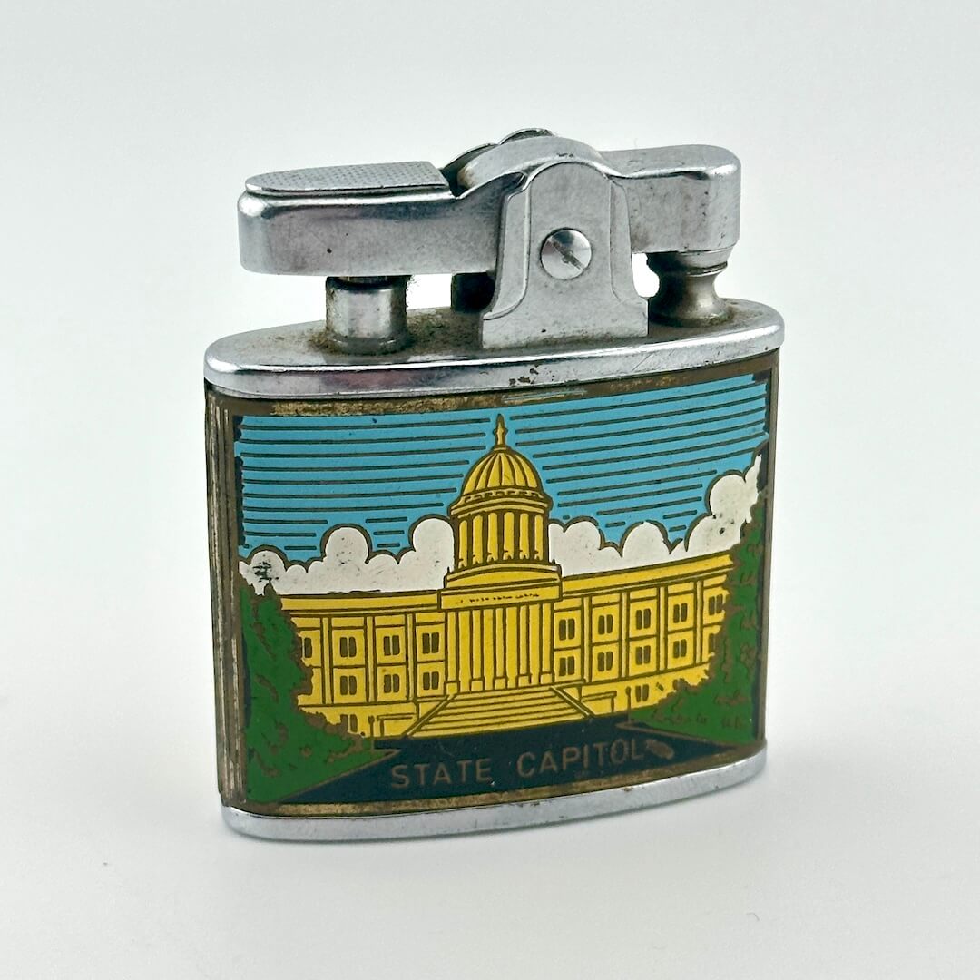 A vintage metal lighter with a silver-toned top and a colorful front panel depicting the Washington State Capitol building.