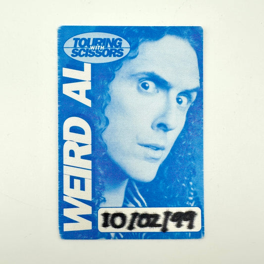 A blue and white pass featuring a stylized portrait of a man with the text 'TOURING WITH SCISSORS' and 'WEIRD AL'.