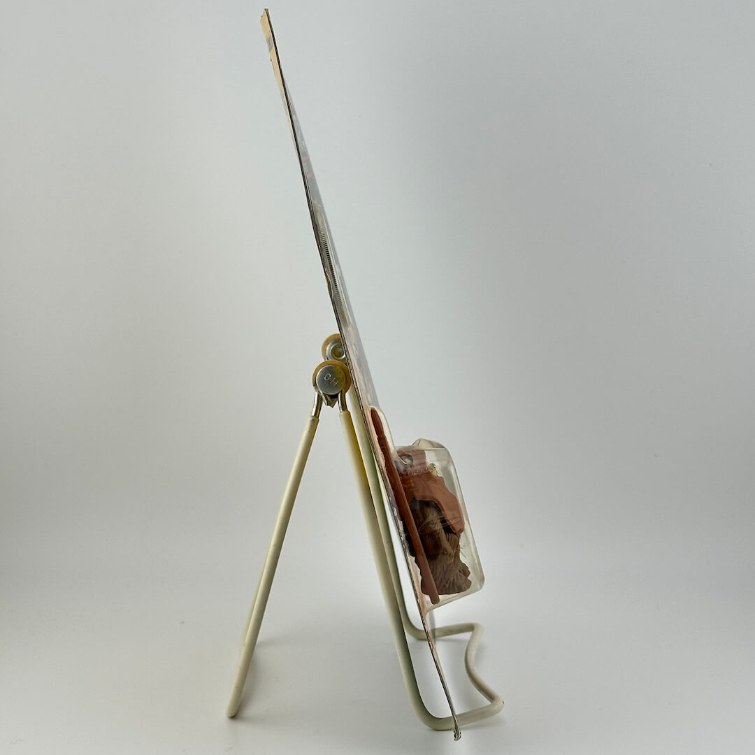 Side view of star wars action figure in packaging on easel against white background.