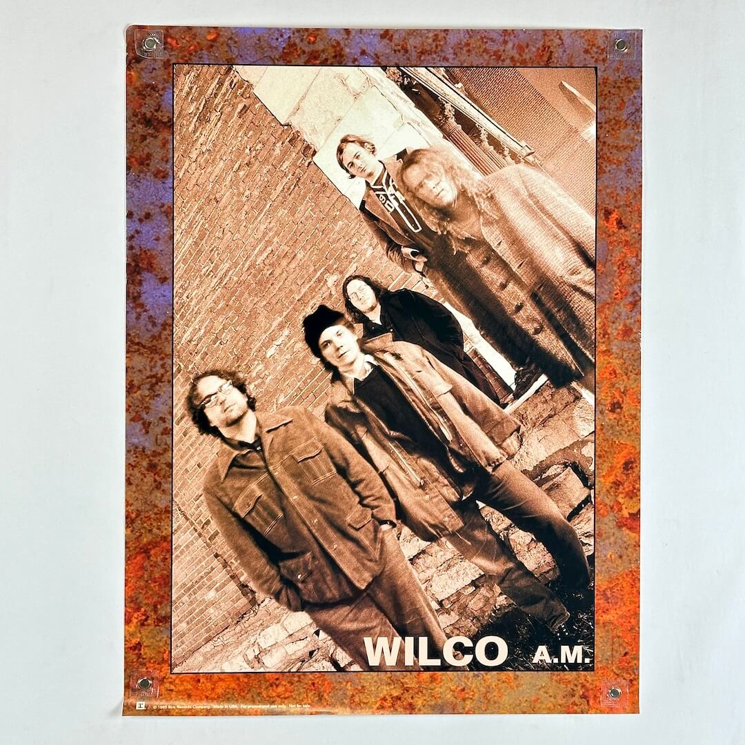 Poster of a band with 'Wilco A.M.' text on a textured border