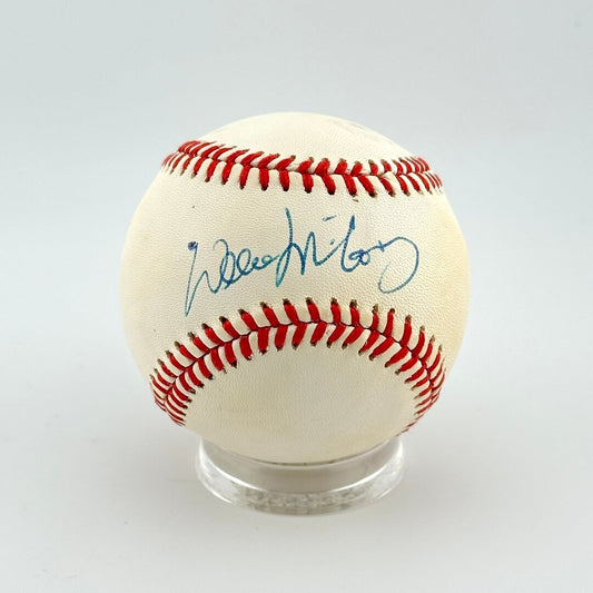Baseball with red stitching on a clear stand against a white background