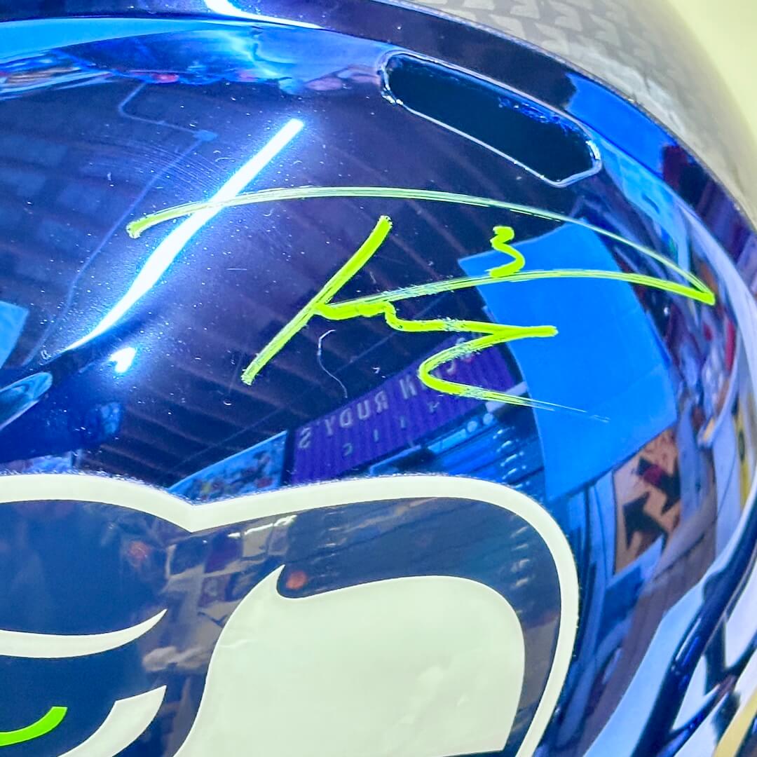 Close up of signature on top of helmet in green marker. 