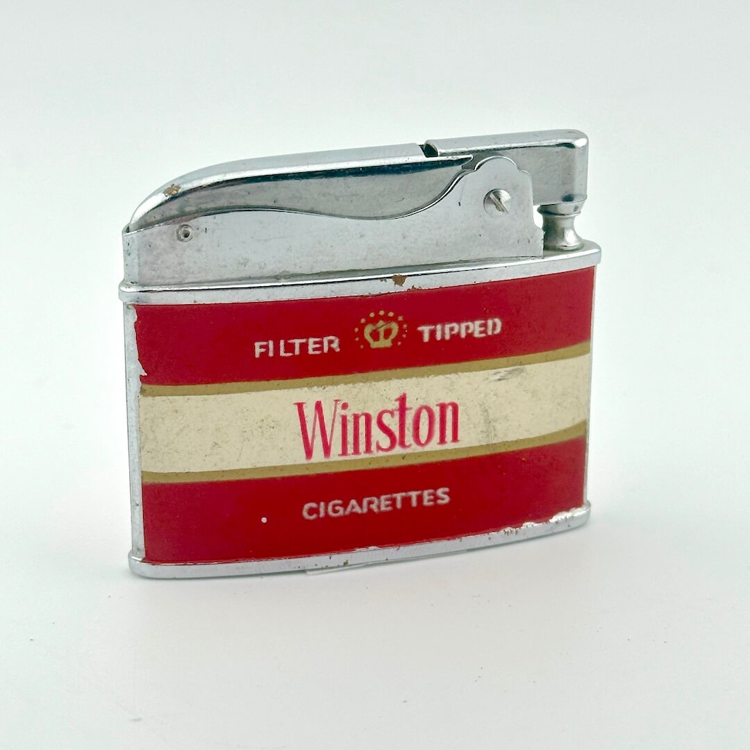 A vintage Winston Cigarettes filter-tipped lighter with a red and cream label and silver metal body.