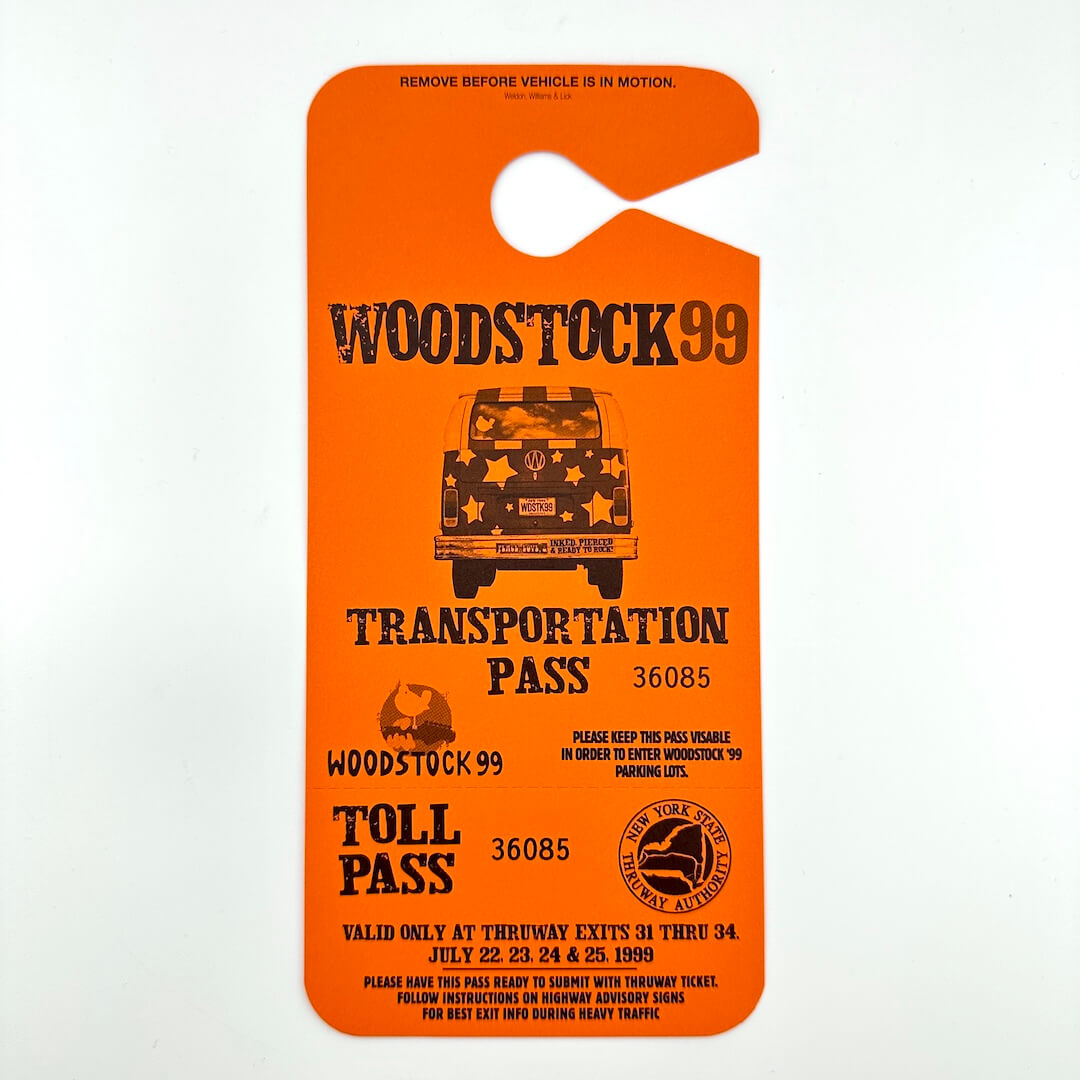 Orange Woodstock 99 Transportation Pass  with black text and image of VW bus in center. 