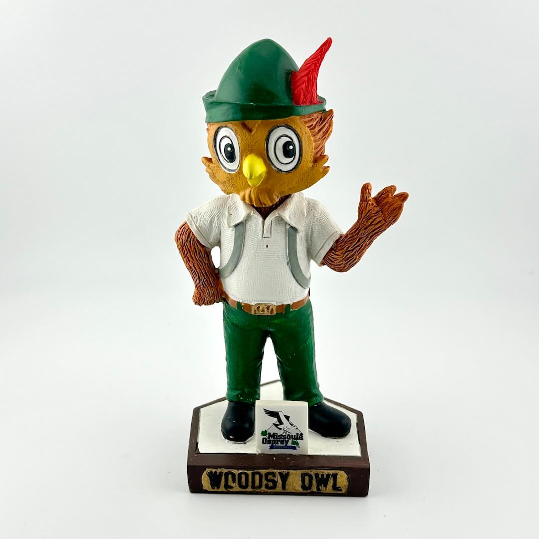 Bobblehead figure of an owl character in a green hat and outfit on a white background