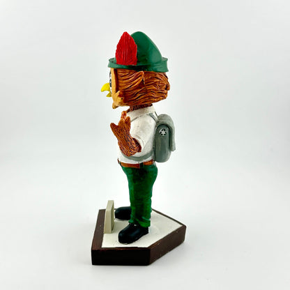 Bobblehead figure of a character with a green hat and red feather on a white background