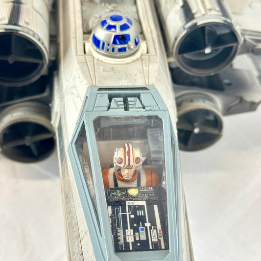 Close-up of a Star Wars X-wing TIE fighter model or toy, showing the cockpit with a small figure inside.