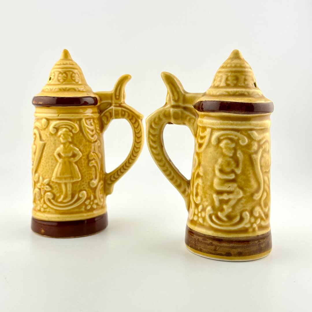 Two ceramic steins with decorative designs on a white background