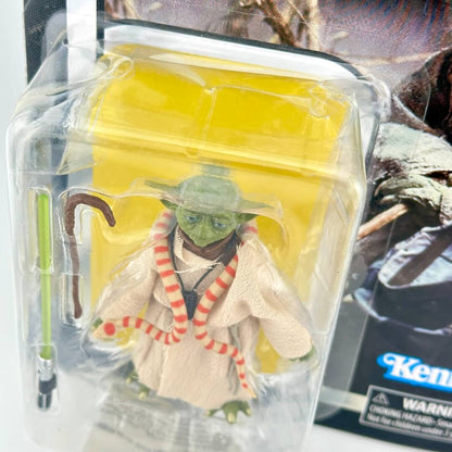 Action figure of Yoda from Star Wars, shown in its original blister packaging with a green lightsaber accessory.