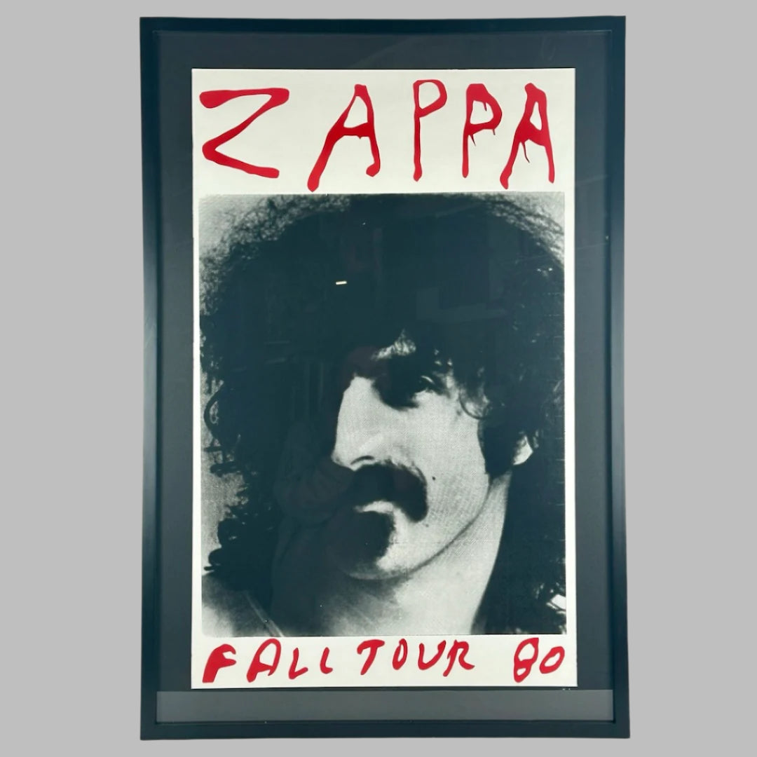 Framed poster with red text "ZAPPA," at top, & "FALL TOUR 80" at bottom. Black & white photo of Zappa in center.