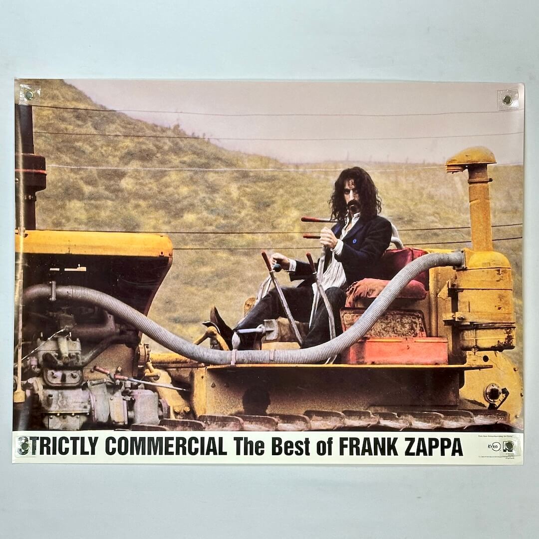 Album cover with Frank Zappa sitting on a large piece of machinery against a mountainous background.