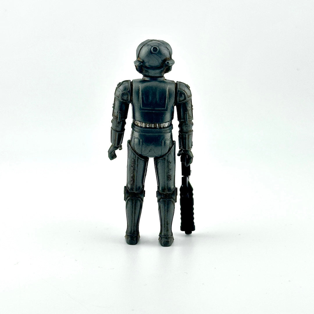 Action figure of gray cyborg holding big black gun against white background. 